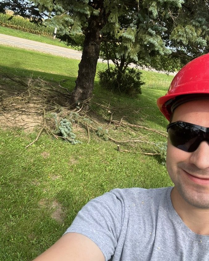 Grant in a hard hat and safety glasses, clearing branches on a job